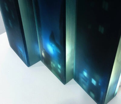 a 3d layered glass trptych artwork portraying a noir urban landscape deep in the heart of the city. Shadowy buildings, glowing streetlights and windows rendered in stacked transluscent layers of glass, creating depth, mystery and cinematic atmosphere