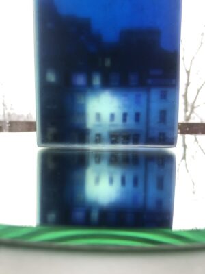 Close up detail of a 3D layered glass artwork depicting tiny buildings under a huge deep blue magical twilight sky