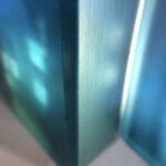 a 3d layered glass trptych artwork portraying a noir urban landscape deep in the heart of the city. Shadowy buildings, glowing streetlights and windows rendered in stacked transluscent layers of glass, creating depth, mystery and cinematic atmosphere